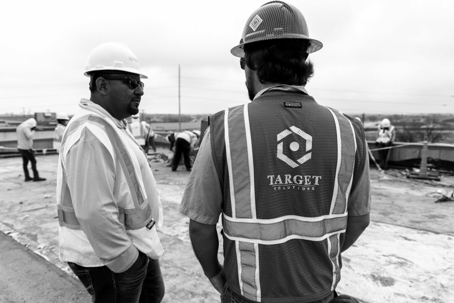 two men wearing hardhats talking to each other at a restoration site