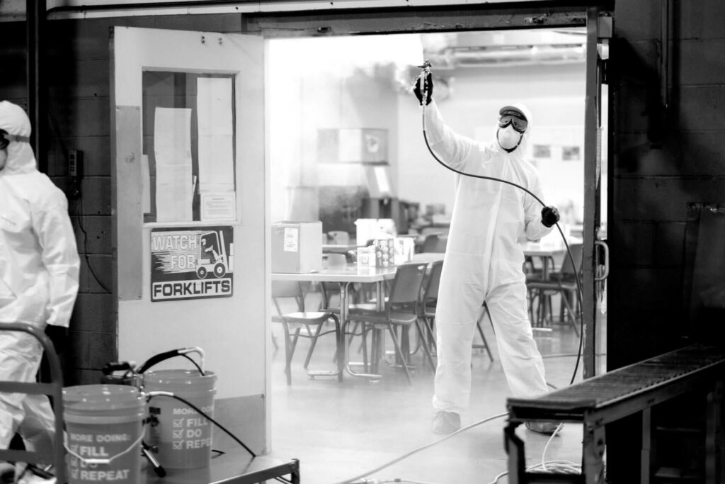 A person in white protective clothing fumigates a room